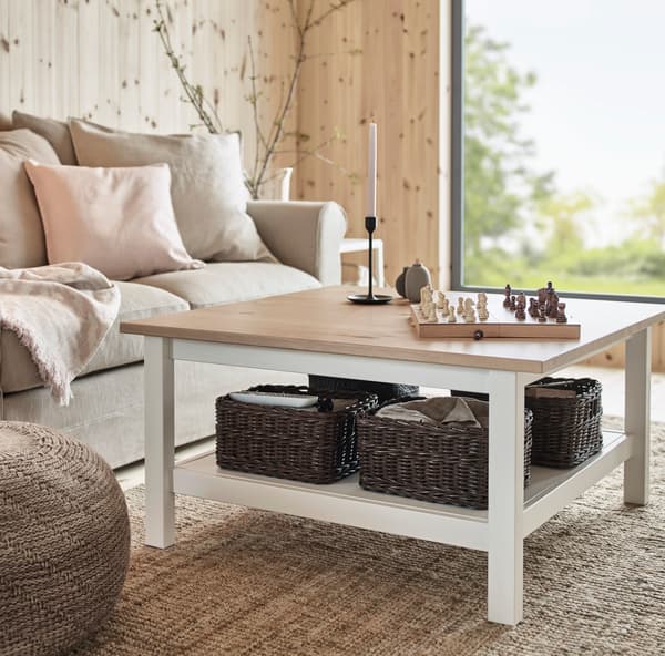 Sofa azul con cojines con diseño negro y blanco, del modelo de IKEA GLOSTAD. Se encuentra en una sala con piso de madera y una mesa blanca IKEA TINGBY, sobre una alfombra TIPHEDE de color gris.
