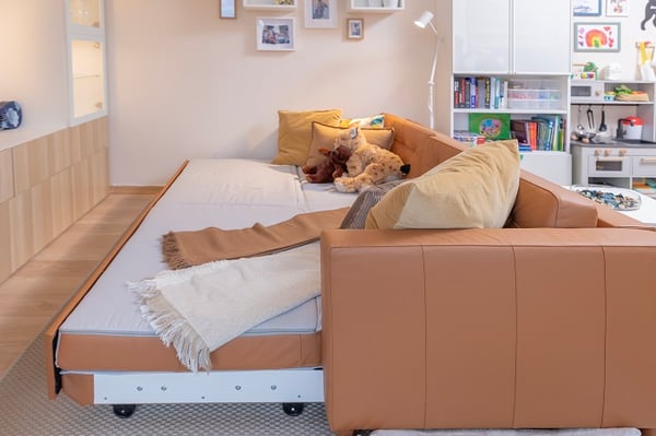 Sofa bed with pillows and blankets in multifunctional living room.