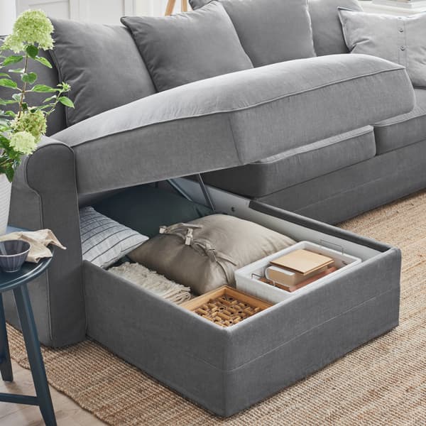 Sofá gris oscuro GRÖNLID donde tiene guardado cosas en su interios, como un cojín y cajas.