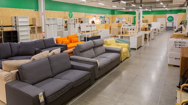 Sofas in multiple colors and styles arranged in a furniture store with shelves and other items in the background.