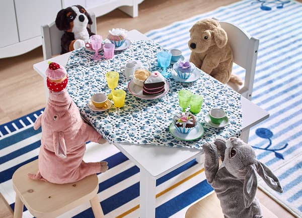 Soft toys sitting around a small table with a tea party set-up.