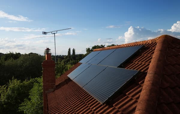 Solar panels mounted on top of the roof of a residential home, with clear bright skies.