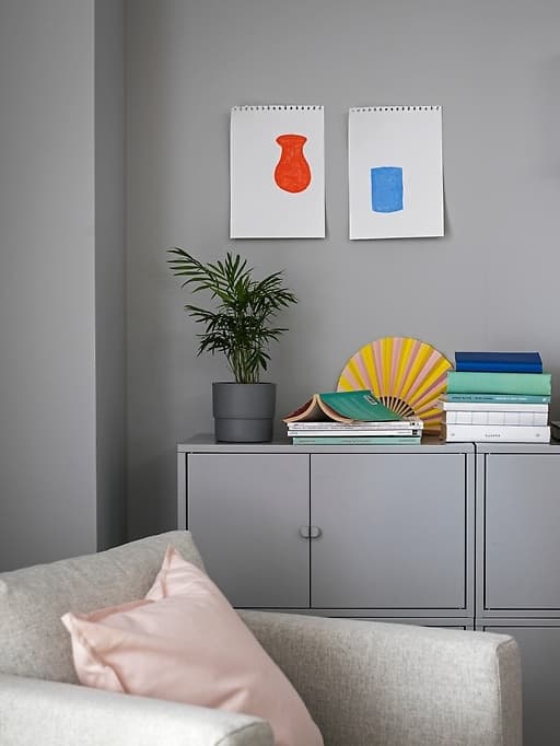 Solución de almacenaje gris sobre pared gris, sillón con cojín rosa.