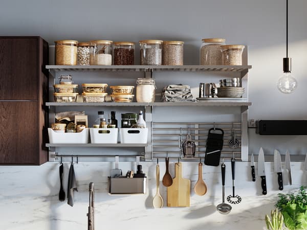 Soluzione da parete KUNGSFORS con barattoli in vetro, scatole e vari utensili da cucina, accanto a un mobile marrone con ante - IKEA.