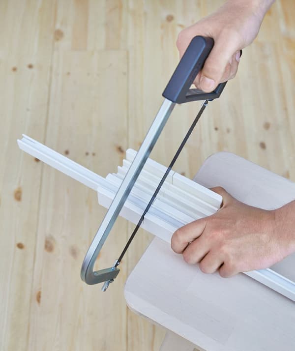 Someone cutting VIDGA track system rail pieces to the right length using a hacksaw.