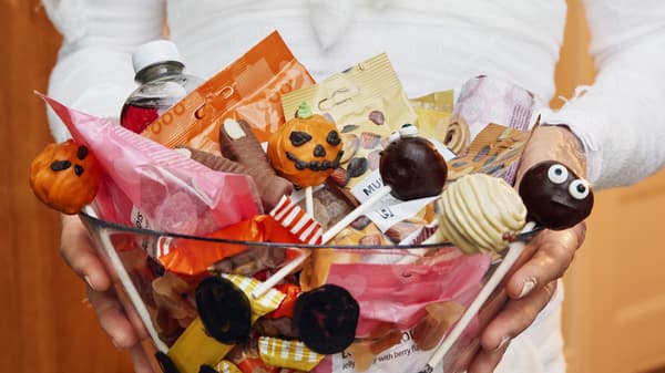 Someone holding a bowl full of Halloween candy and treats