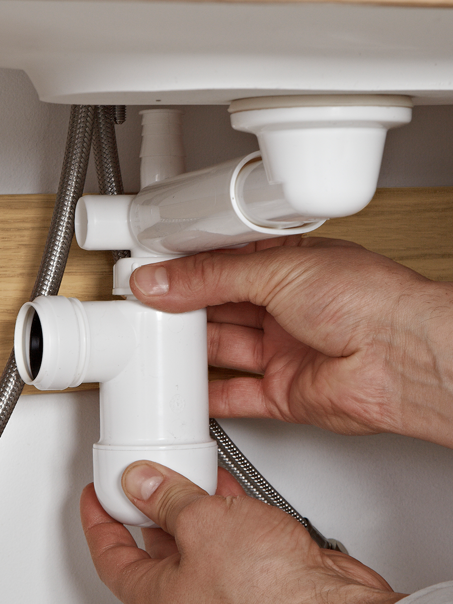 Someone is fixing pipes in a bathroom cabinet