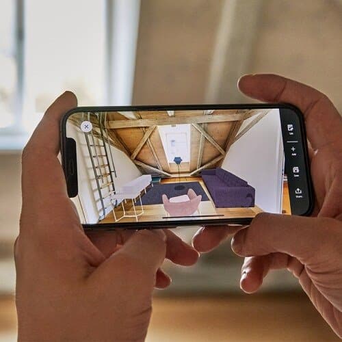 Someone opens the IKEA Kreativ app on his phone and designs a room with furniture.