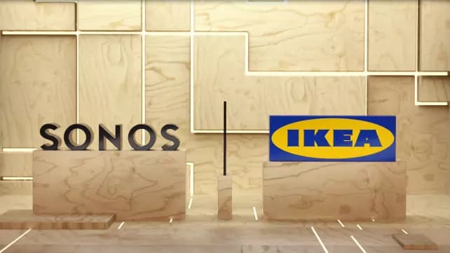 Sonos och IKEA loggan står på en varsin box av trä framför en vägg av trä