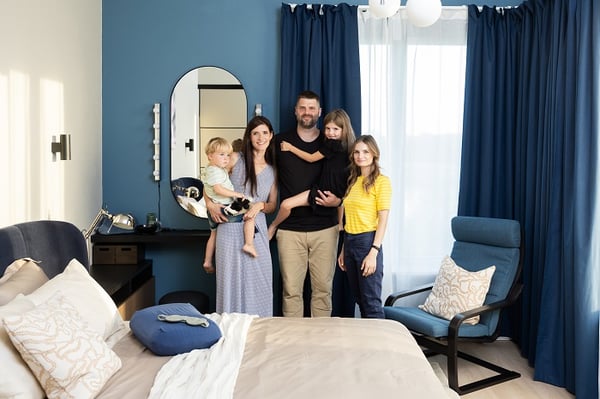 Современная семья вместе в стильном синем интерьере спальни с естественным освещением