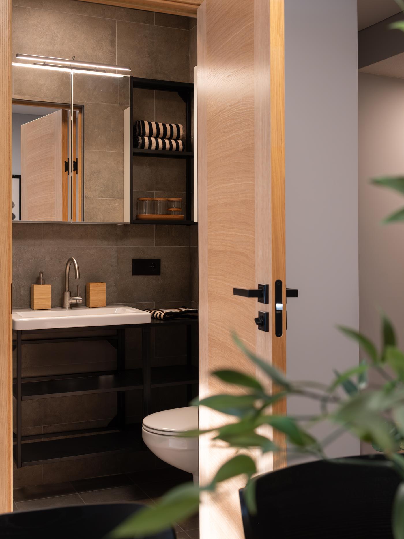 Современная ванная комната с темно-серым настенным туалетным столиком и зеркальным шкафчиком над ним.