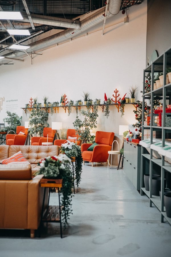 Современный коворкинг IKEA Hej! с длинными рабочими столами, оранжевыми стульями и декоративным освещением.