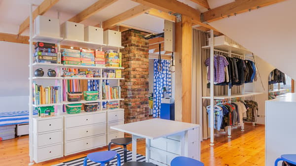Spacious kids room with storage shelves, table and open wardrobe