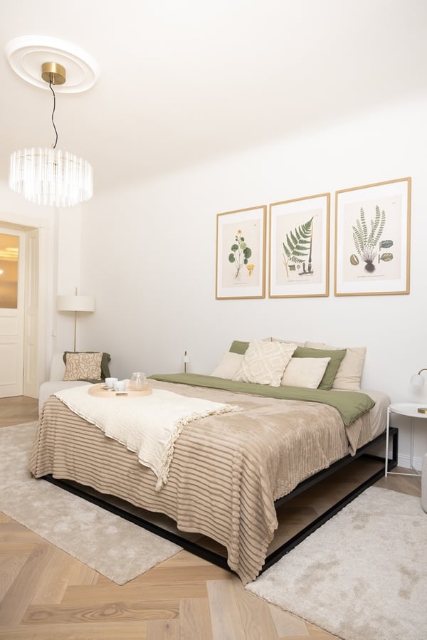 Спальня с двуспальной кроватью, нейтральным текстилем, настенным декором и потолочным светильником.