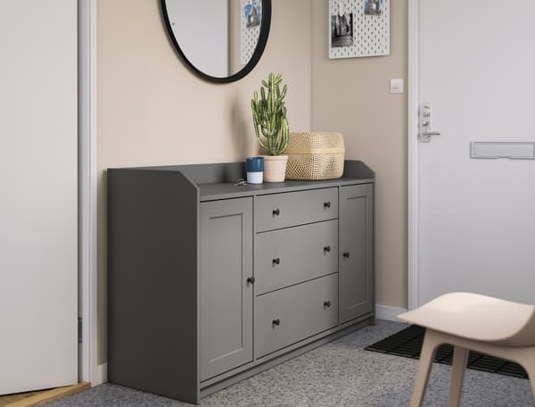 Sparsely furnished hallway with a mirror, a lone chair and a grey HAUGA storage unit placed next to the front door.