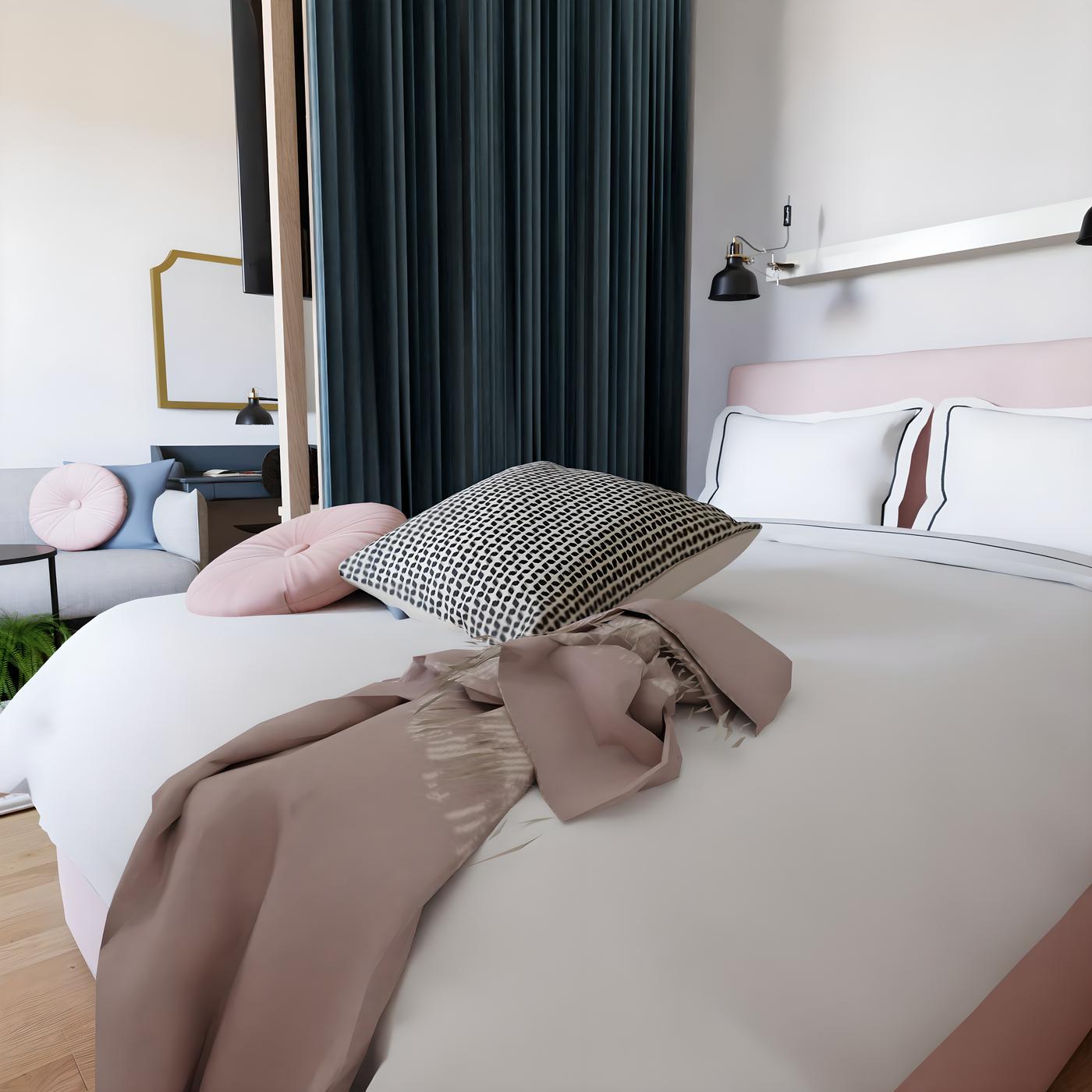 Spavaća soba s bijelim krevetom, ružičastim i crnim jastucima, te sivom dekom. U pozadini su tamne zavjese i radni stol s ogledalom.