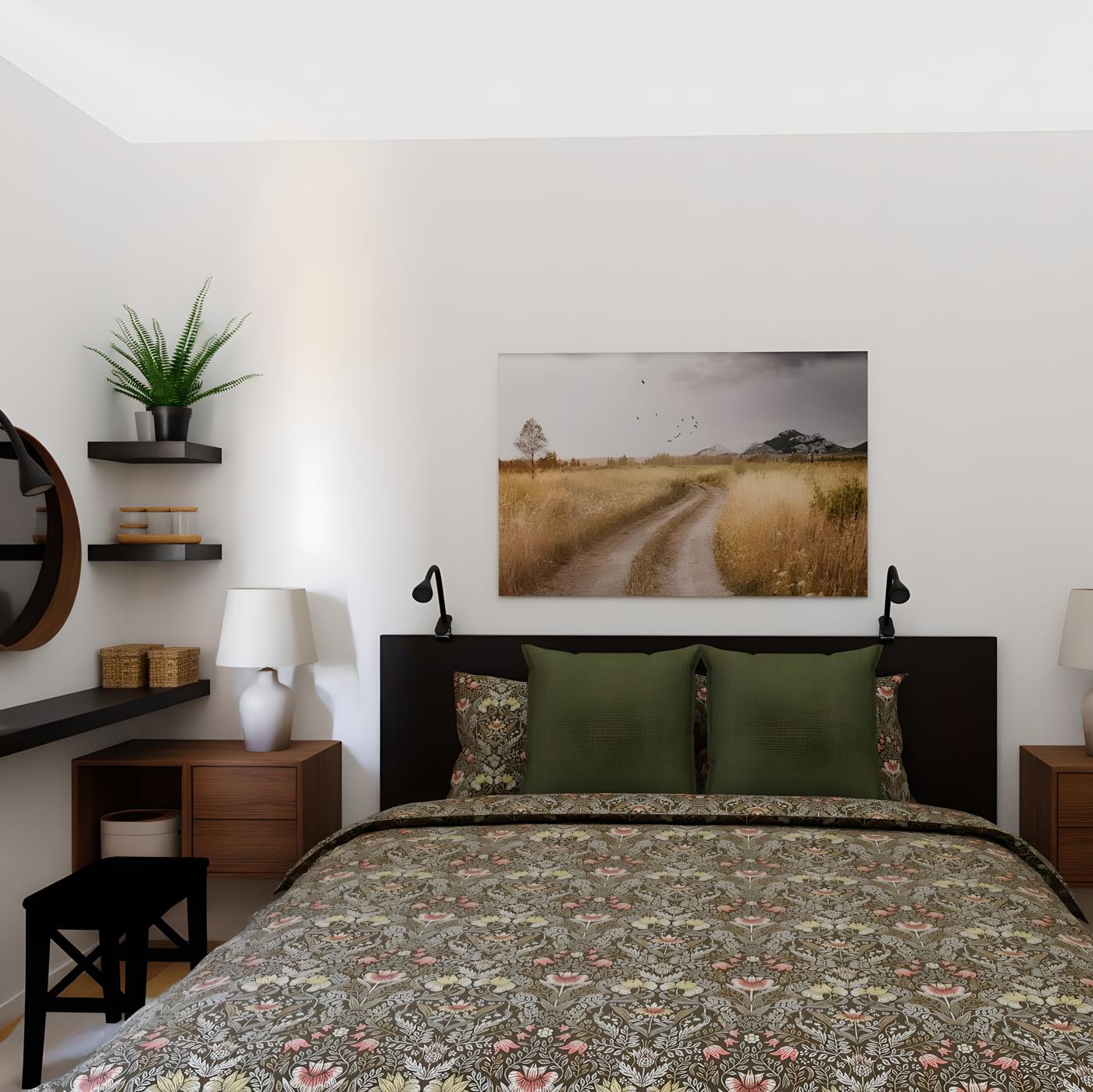 Spavaća soba s krevetom s cvjetnom posteljinom i zelenim jastucima, slikom seoskog puta iznad kreveta, noćnim ormarićima s lampama te policama s biljkama i ogledalom.