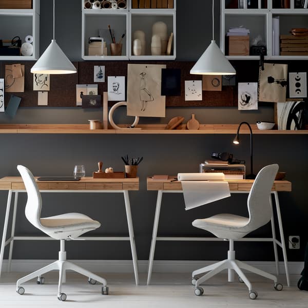 Spazio di lavoro con due sedie da ufficio LÅNGFJÄLL vicino a scrivanie LILLÅSEN, con scaffali, bacheche e lampade a sospensione bianche - IKEA.