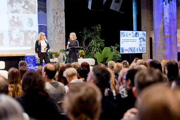 Speakers presenting on stage at the IKEA for Business conference event in front of a seated audience, with presentation screens and greenery in the background.