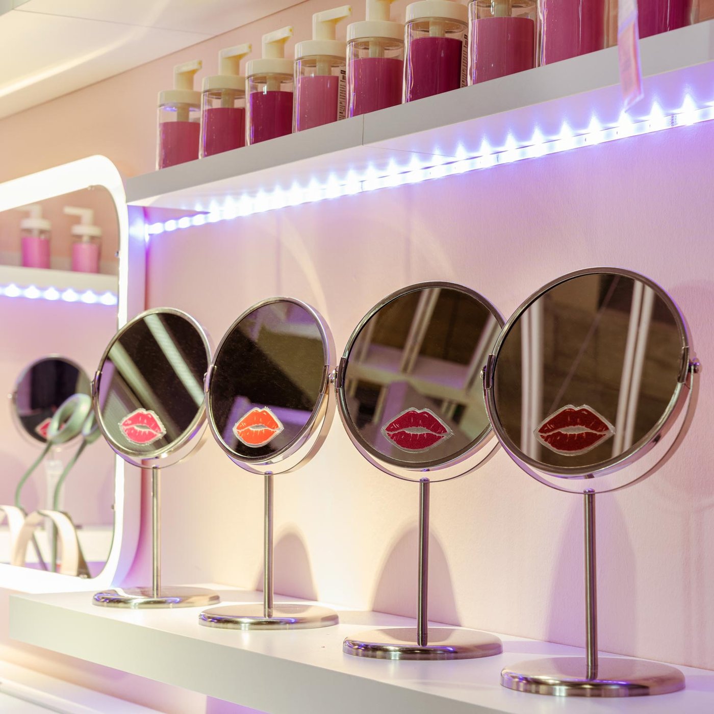 Specchi in acciao inox TRENSUM decorati con sticker di un bacio posizionati uno accanto all'altro su una mensola illuminata da luci a led.