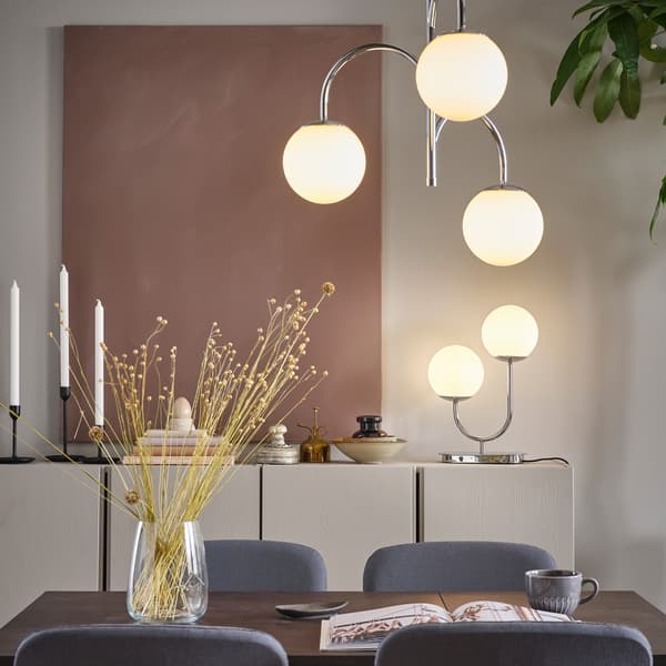 Spisebord med spisebordsstole og lamper omkring.