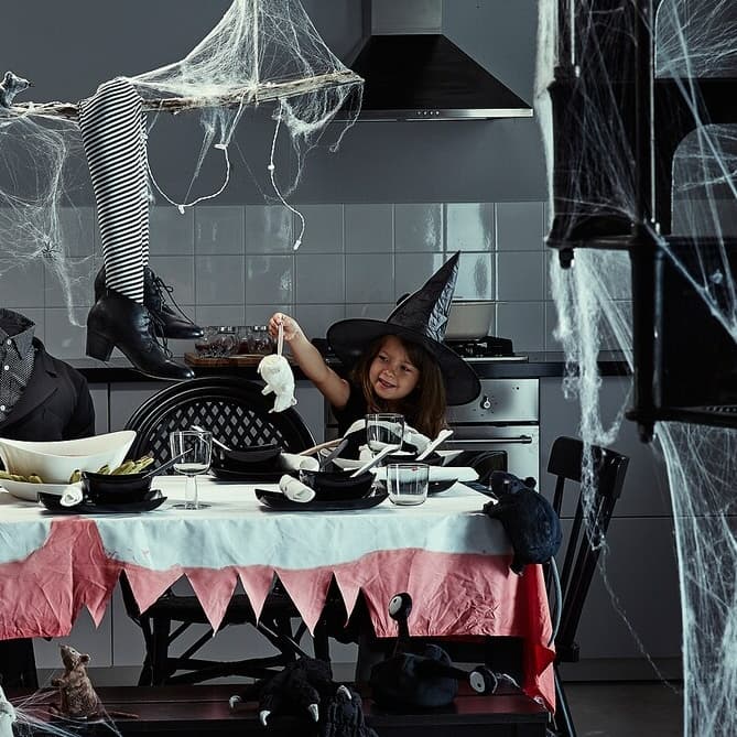 Spooky table decorated with black plates and cutlery and spider webs.