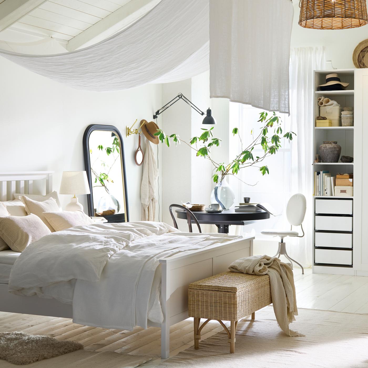 سرير HEMNES مزدوج أبيض في غرفة نوم بيضاء جيدة التهوية بها طاولة INGATORP قابلة للتمديد سوداء بالقرب من نافذة بالخلف.