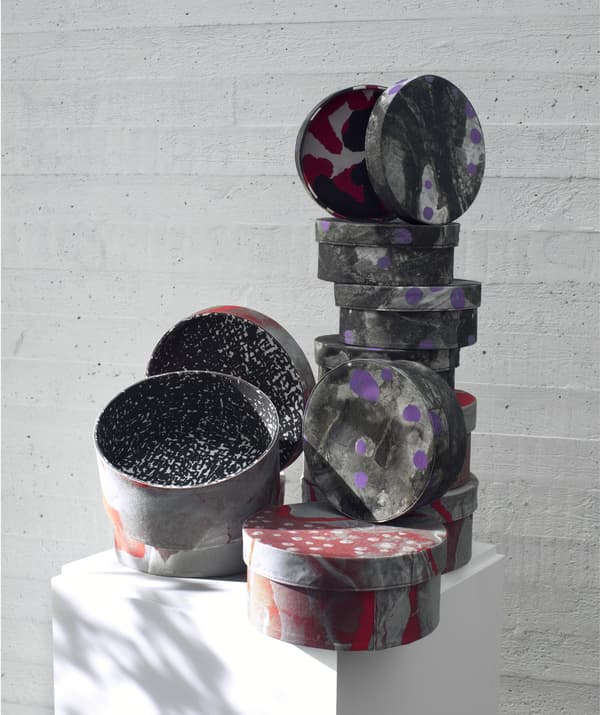 Stacks of patterned grey, purple and red boxes in different sizes with lids.