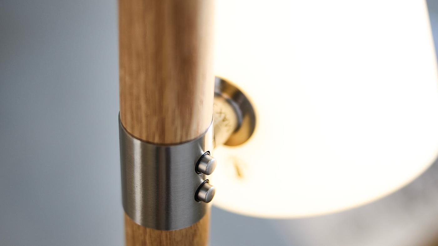 Ståldetaljer på en lampa med ekstång. I bakgrunden syns en vit glaskupa. 