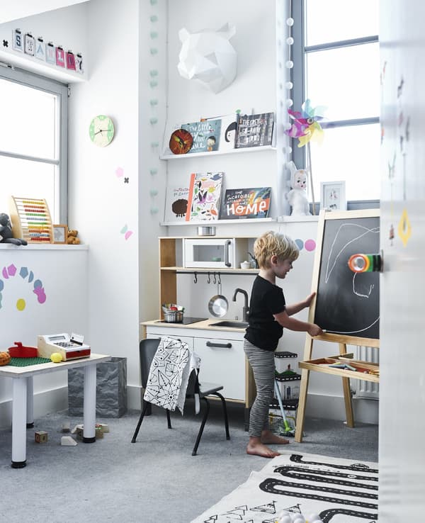 Stanley, a small boy, playing in his bedroom as he draws with chalk on his easel.