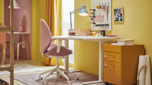 Stanza dai colori vivaci con uno spazio di lavoro il cui elemento centrale è costituito da un tavolo TROTTEN bianco e da una sedia da ufficio HATTEFJÄLL marrone chiaro e rosa - IKEA.