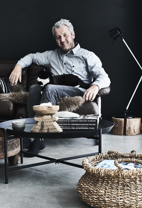 Stig sitting in a leather sofa with a black and white cat on his lap.