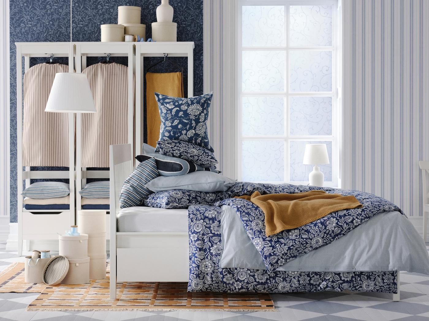 Stilvoll eingerichtetes Schlafzimmer mit gemustertem IKEA Bettbezug, gestapelten Kissen, offener Garderobe und skandinavischem Design – gemütliche und funktionale Schlafzimmereinrichtung von IKEA.







