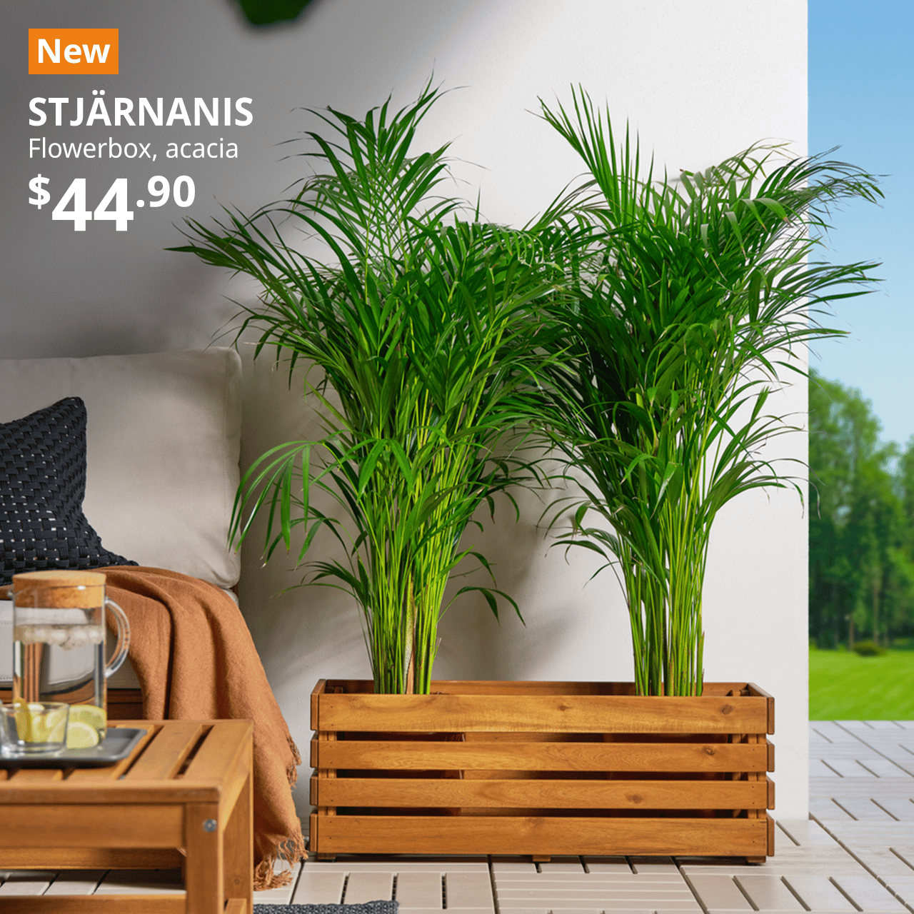 STJARNANIS flower box resting on a RUNNEN floor decking in an outdoor area, with two large green plants placed inside. Text on image reads New with a orange box, STJARNANIS, flowerbox, acacia, $44.90.