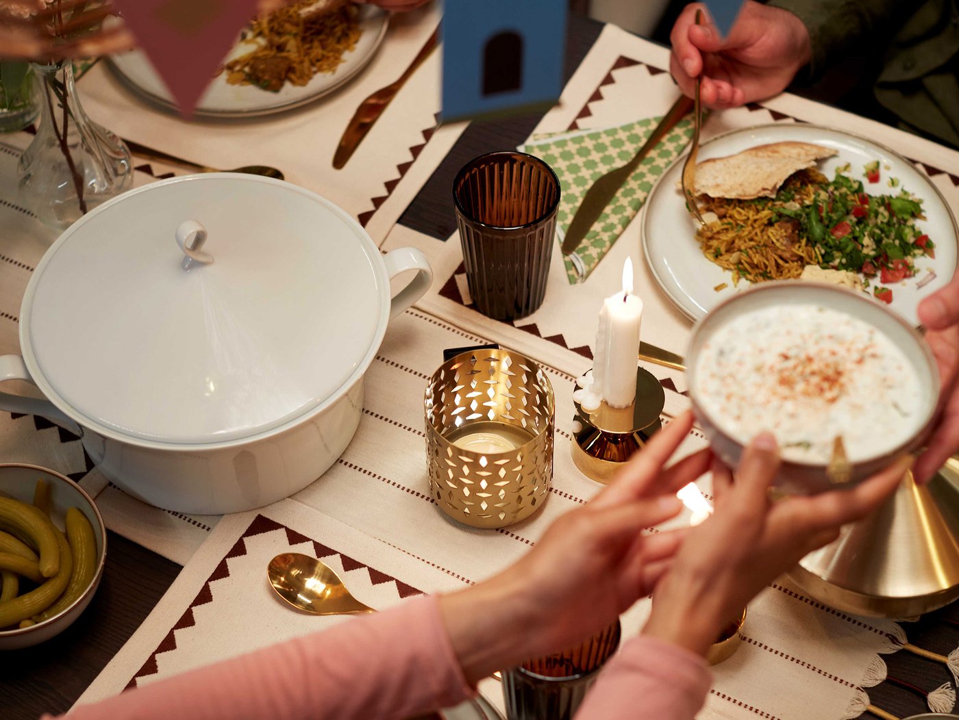 Sto postavljen za ručak. Dvoje ljudi koji dodaju hranu jedan drugom.