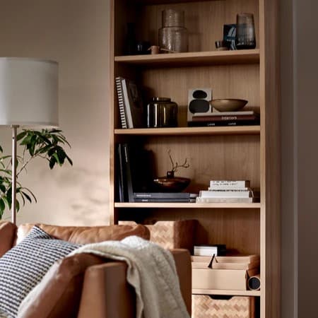 STOCKHOLM-malliston kolmen istuttava sohva, jonka takana on TONSTAD-kirjahylly kirjoineen ja koriste-esineineen.