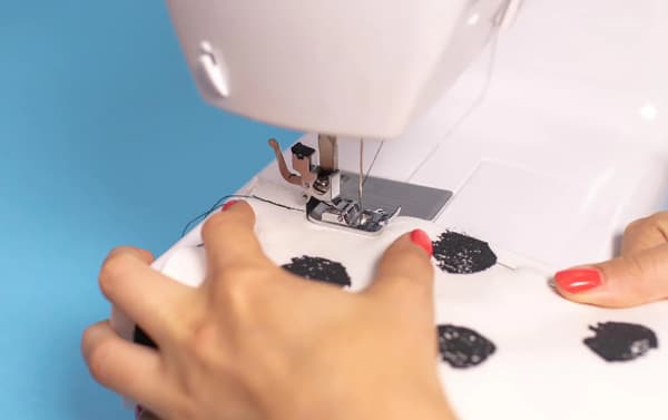 Stoffteile werden mittels Nähmaschine zusammengenäht.