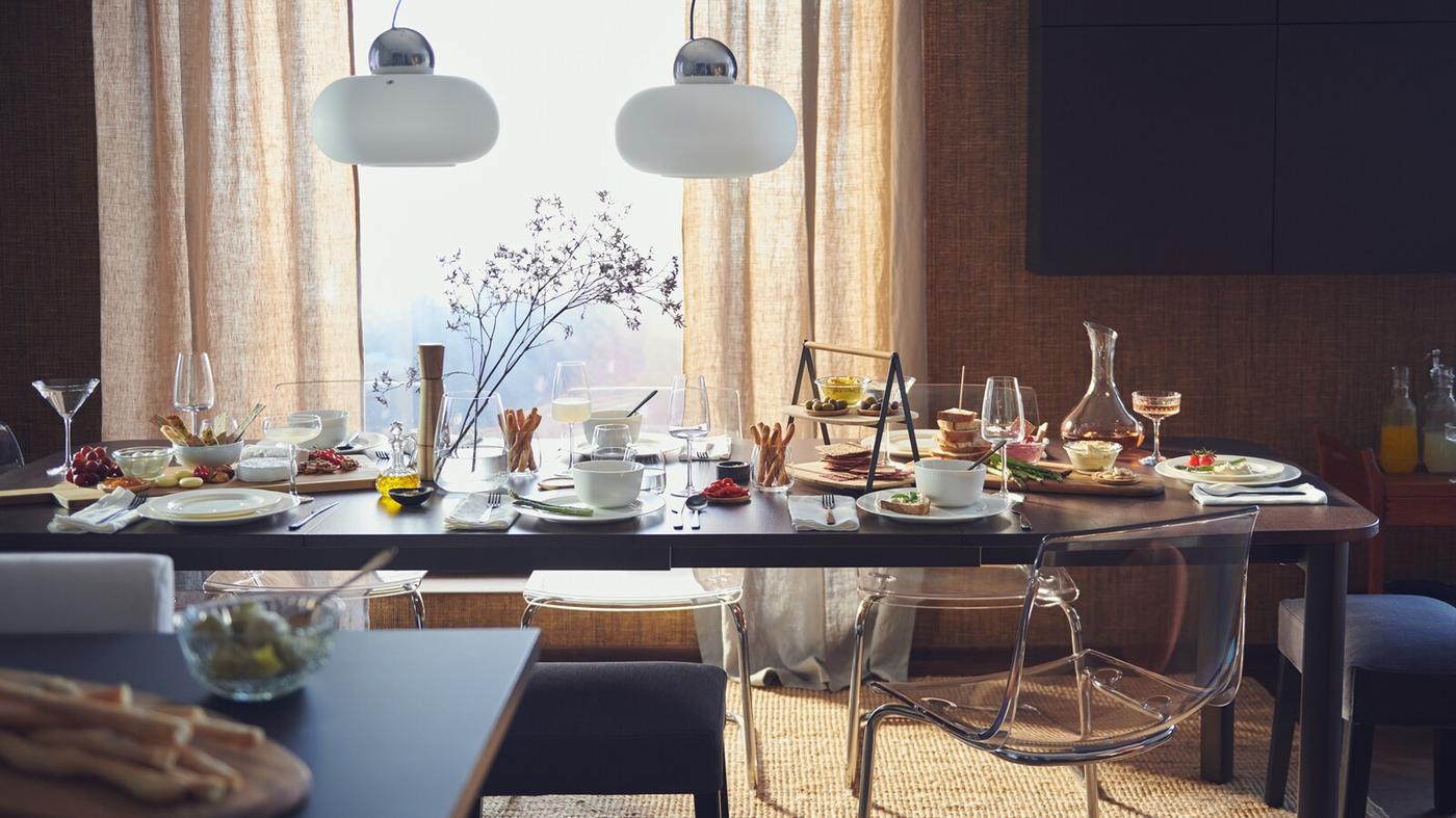 stół pod oknem zastawioany naczyniami i kieliszkami