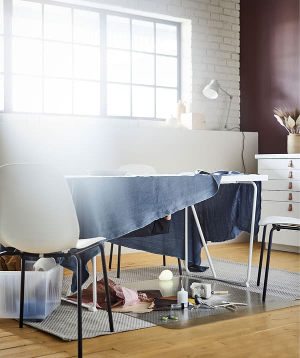 Stol u dnevnoj sobi s tkaninom koja visi sa strana i tako uokviruje improvizirani prostor za crtanje i slično.