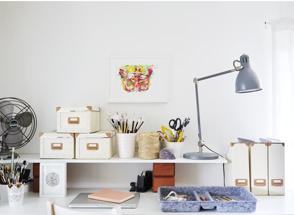 Storage boxes, a lamp and trays on a desk.