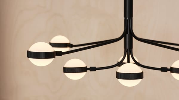 STORSLINGA LED chandelier with spherical heads hangs from a ceiling against a wooden backdrop.
