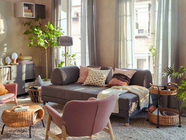 Stue, der ligner sig selv igen efter at have fungeret som gæsteværelse – med FLOTTEBO sovesofa, planter, tekstiler og et stort tæppe.
