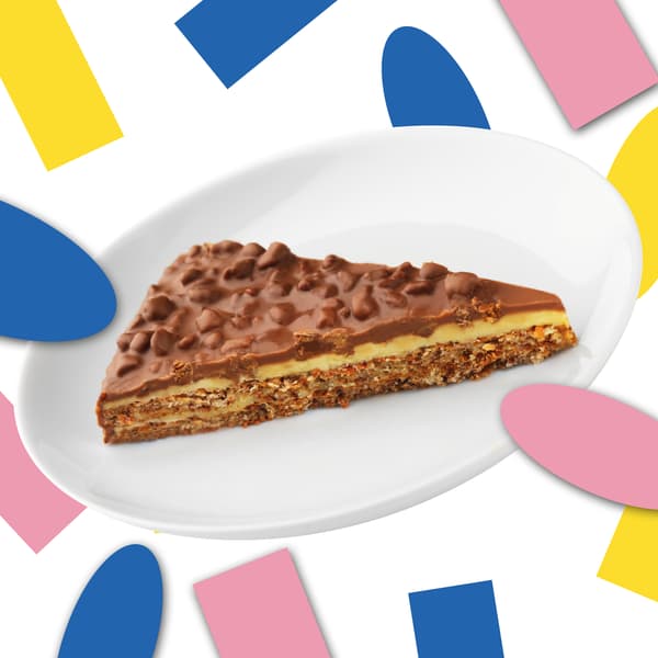 Stück Daimtorte auf einem weißen Teller vor einem weißen Hintergrund mit buntem Konfetti.