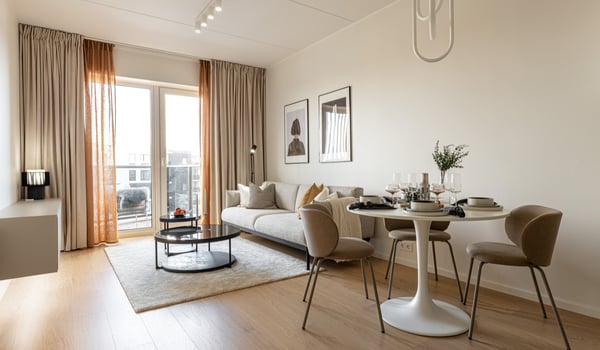 Stylish apartment living room with beige sofa, round dining table, and balcony view.