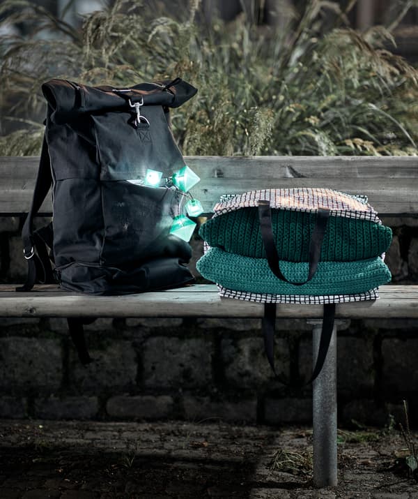 Suasana waktu senja dengan bangku panjang awam yang mempunyai beg galas, lampu kelap-kelip yang dinyalakan di dalam poketnya dan beg yang berisi tekstil.