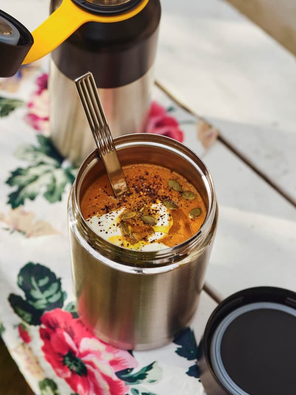 Sütőtök-krémlevessel teli EFTERFRÅGAD vákuumos ételtartót látunk egy fehér asztalon, a háttérben pedig egy HETLEVRAD termosz áll.