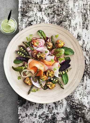 Summer salad with veggie balls served on a wooden plate, seen from above.