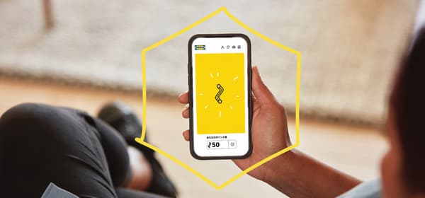 スマートフォンにイケアのリワードプログラムのイメージ画像が表示されており、そのスマートフォンを見ている人がいる
