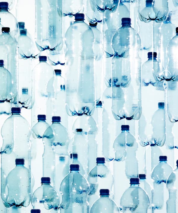 Superposition de multiples bouteilles en plastique transparent à capsule bleue.