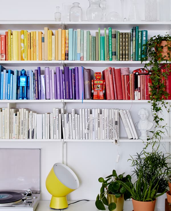 Sur les tablettes blanches, les livres sont rangés par couleur, créant une impression artistique.